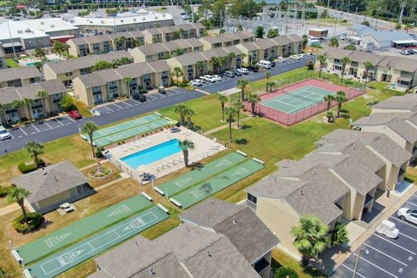 Pool, recreational fields, and grassy field surrounded by grey buildings at Gulf Highlands Beach Resort.