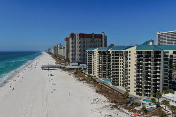 Buildings of Sunbird Beach Resort along a sandy beach on a sunny day.