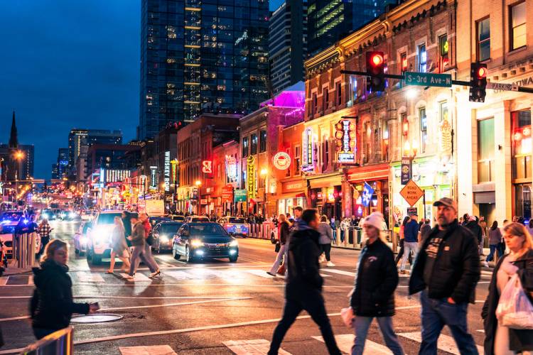 People walking across Broadway at night in Nashville, TN