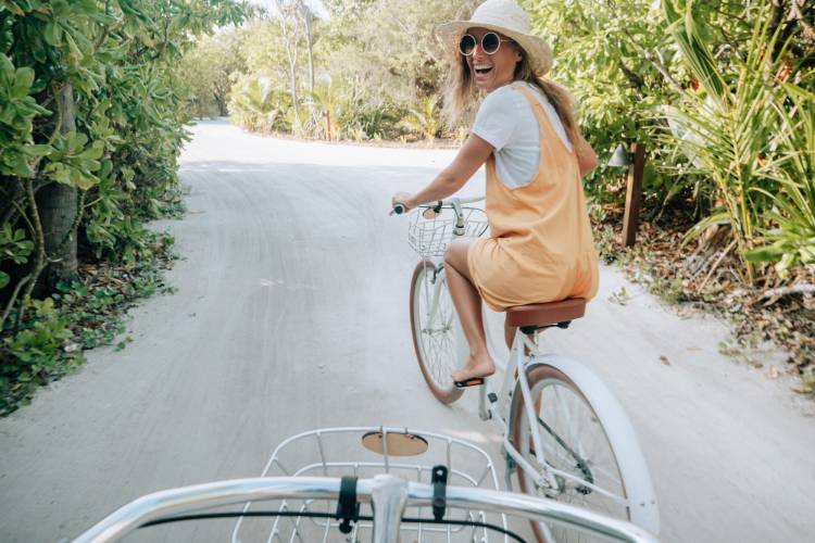 A woman looks back and smiles from a bike on a road