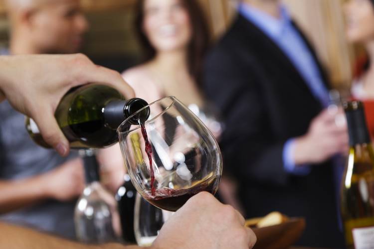 A person pours a glass of wine at a tasting