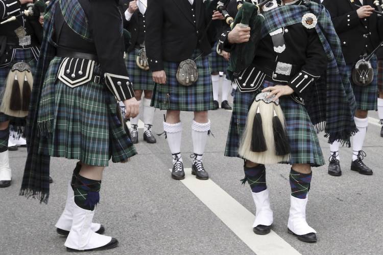 People dressed in Scottish kilts walking down a street in a parade