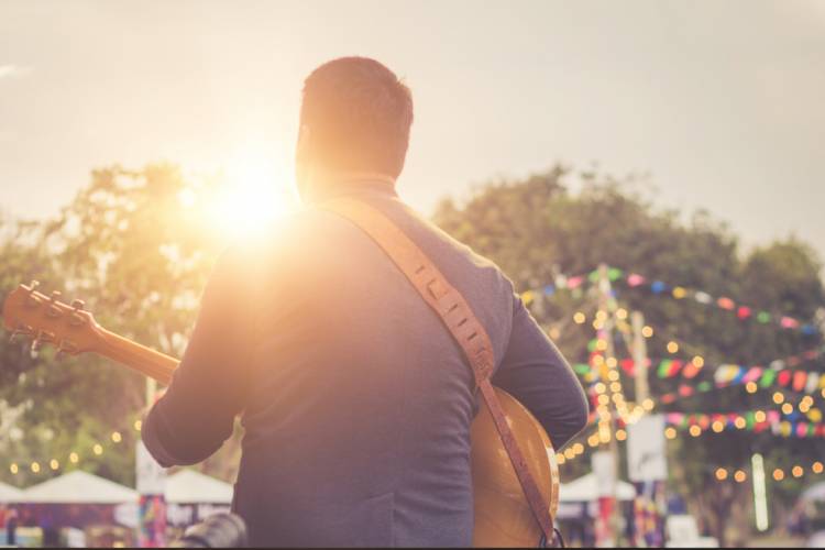 man playing guitar outside at a festival