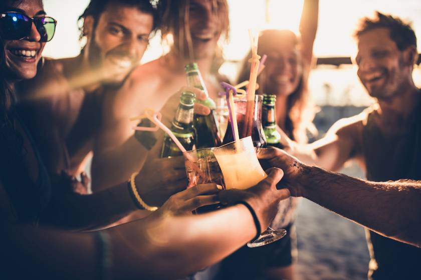 Friends out at a beach bar toasting with various drinks in hand