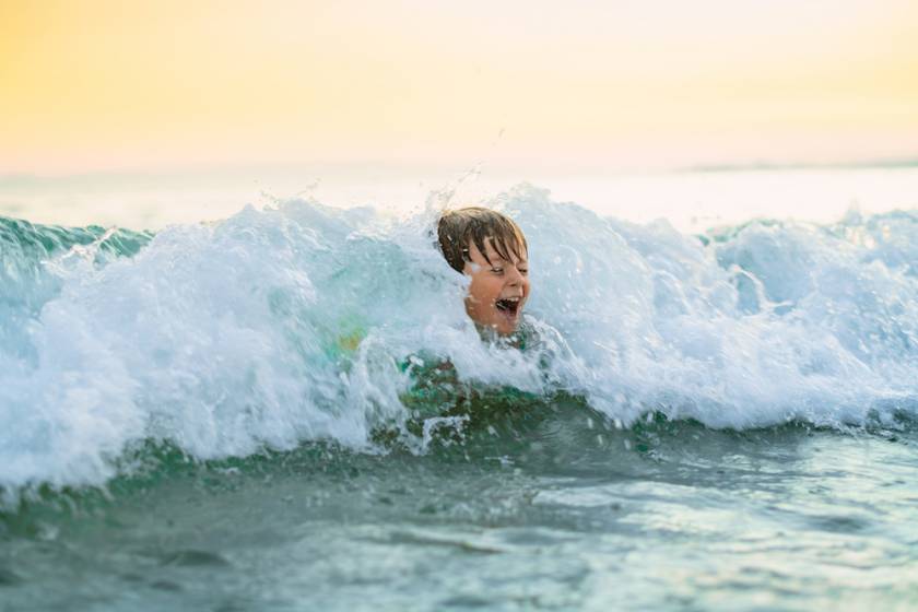 little boy in waves at beach
